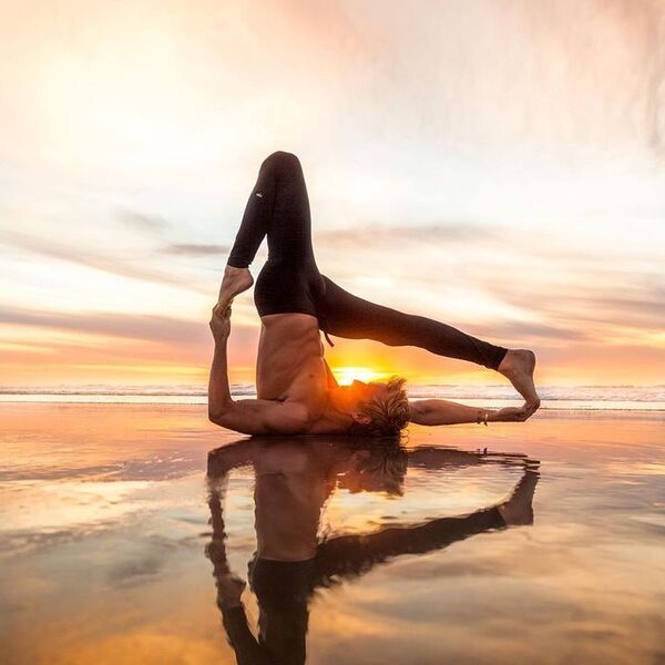 घर में वयस्क व्यक्ति योग मैट पर हल्का स्ट्रेच करते हुए